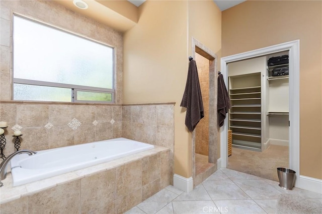 full bath featuring a walk in closet, a garden tub, a tile shower, and tile patterned floors