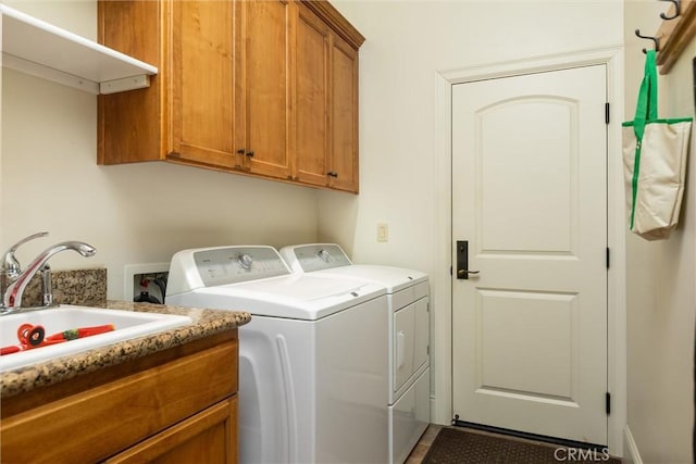 washroom with cabinet space, washer and dryer, and a sink