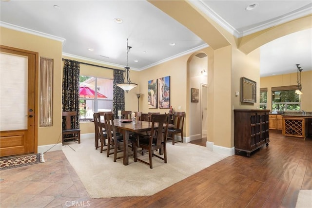 dining area with arched walkways, crown molding, baseboards, and recessed lighting