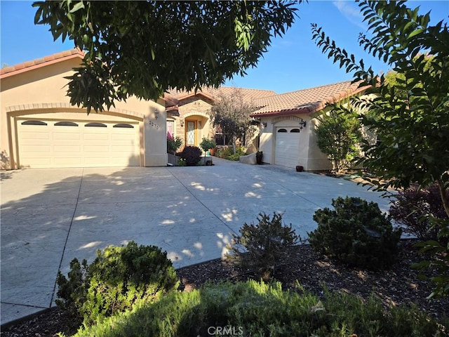 mediterranean / spanish home featuring a garage, stone siding, driveway, and stucco siding