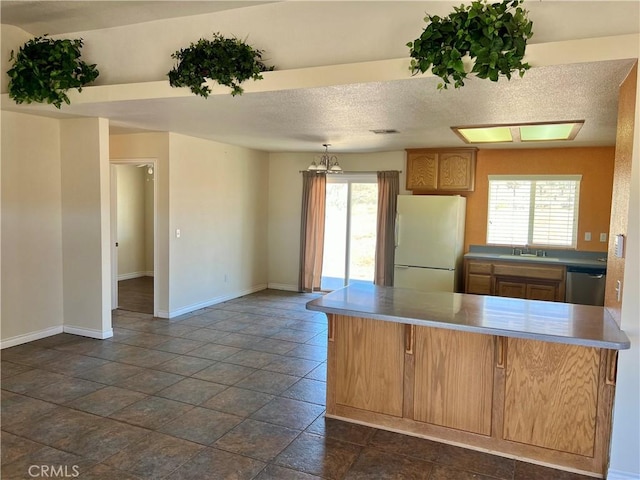 kitchen with pendant lighting, a textured ceiling, stainless steel dishwasher, kitchen peninsula, and white fridge