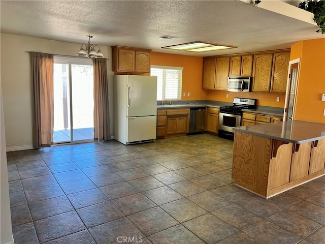 kitchen featuring appliances with stainless steel finishes, an inviting chandelier, a kitchen bar, decorative light fixtures, and kitchen peninsula