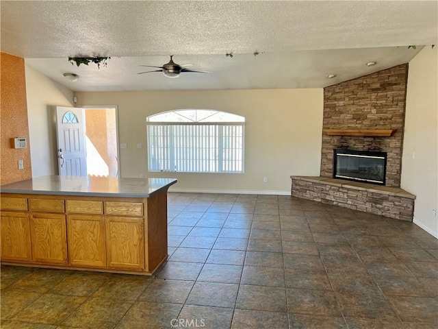 kitchen featuring lofted ceiling, a textured ceiling, a fireplace, and ceiling fan