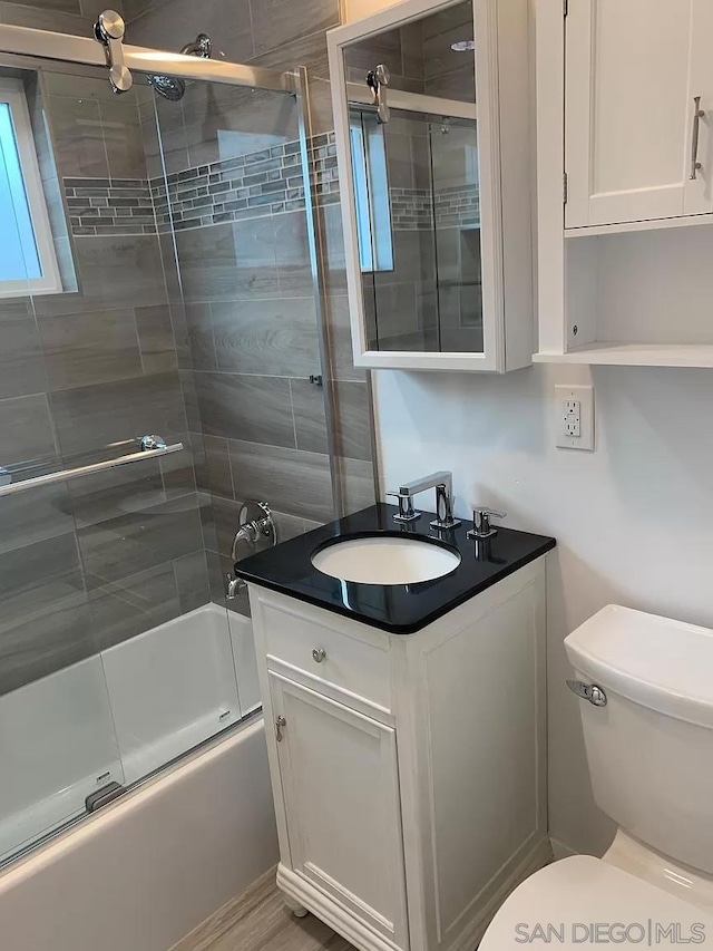 full bathroom featuring vanity, toilet, and bath / shower combo with glass door