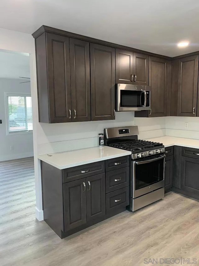 kitchen with light hardwood / wood-style floors, stainless steel appliances, and dark brown cabinets