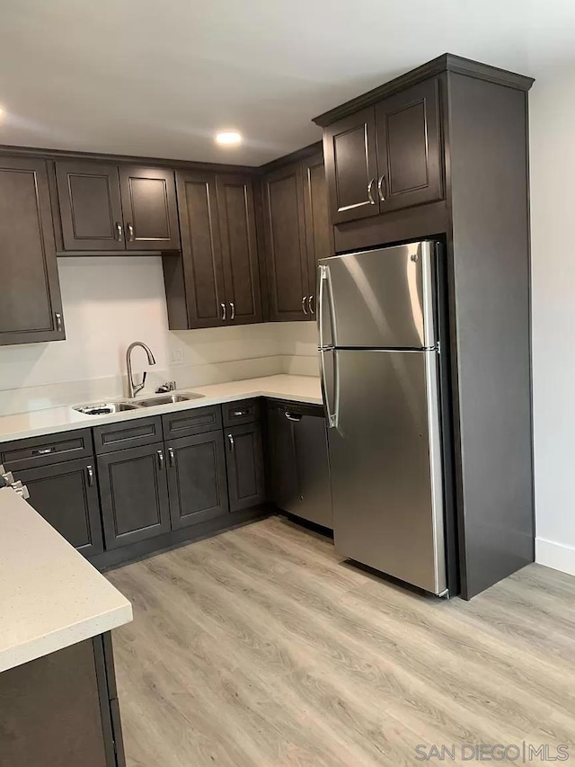 kitchen featuring light hardwood / wood-style floors, dark brown cabinetry, sink, and stainless steel fridge