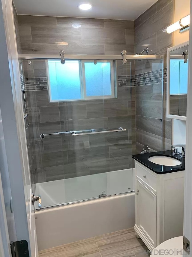 full bathroom with vanity, hardwood / wood-style floors, shower / bath combination with glass door, and toilet