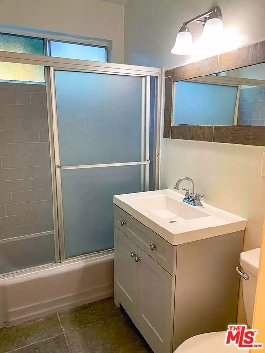 full bathroom with toilet, combined bath / shower with glass door, and vanity