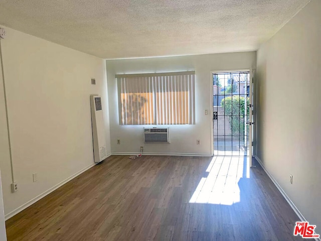 unfurnished room featuring a textured ceiling, a wall unit AC, and wood-type flooring