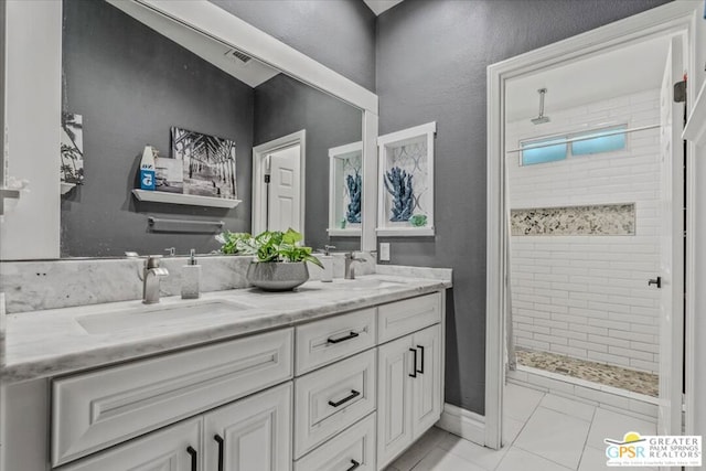 bathroom featuring vanity, a tile shower, and tile patterned flooring