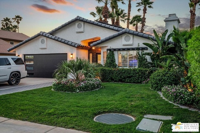 view of front of home with a garage and a lawn