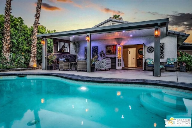 pool at dusk featuring a patio and outdoor lounge area