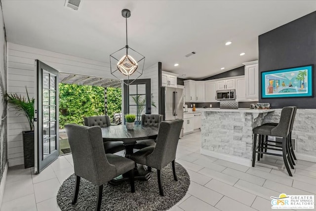 tiled dining area featuring a healthy amount of sunlight and vaulted ceiling