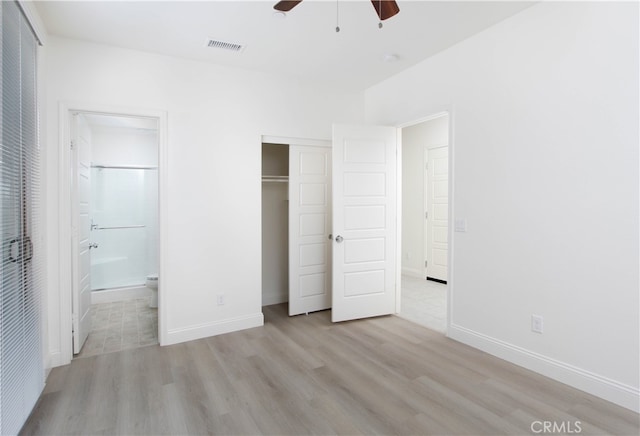 unfurnished bedroom featuring a closet, ensuite bathroom, light hardwood / wood-style floors, and ceiling fan