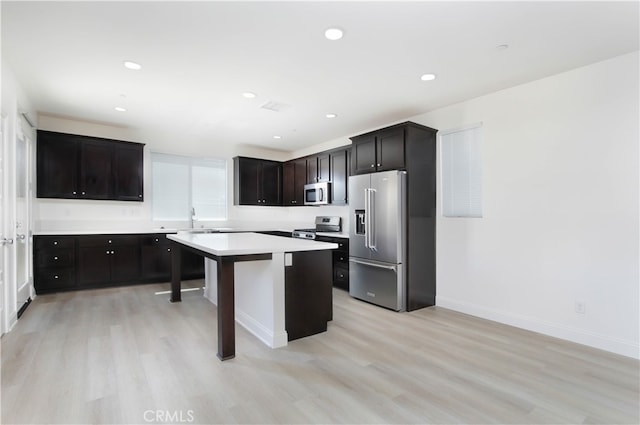 kitchen featuring a kitchen breakfast bar, a center island, stainless steel appliances, and light wood-type flooring