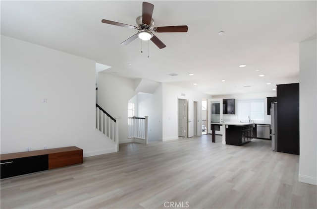 unfurnished living room with light hardwood / wood-style flooring, sink, and ceiling fan