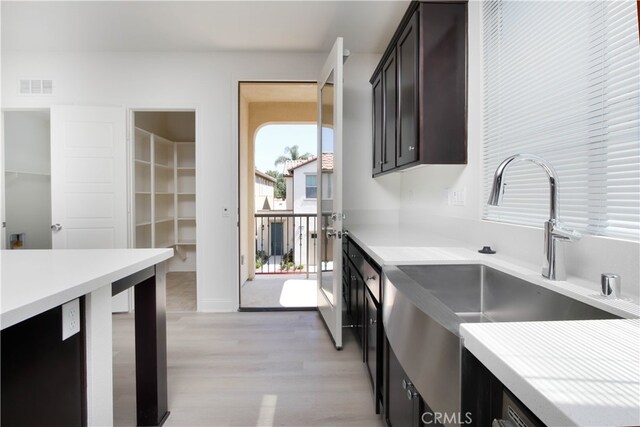 kitchen with light hardwood / wood-style floors, sink, and dark brown cabinets