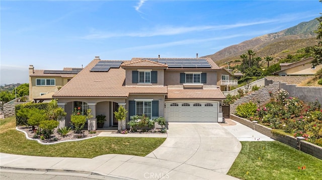 view of front of house with a front lawn, a garage, a mountain view, and solar panels