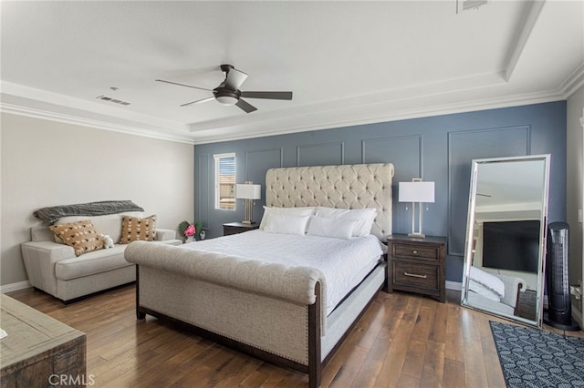 bedroom with crown molding, dark wood-type flooring, ceiling fan, and a raised ceiling