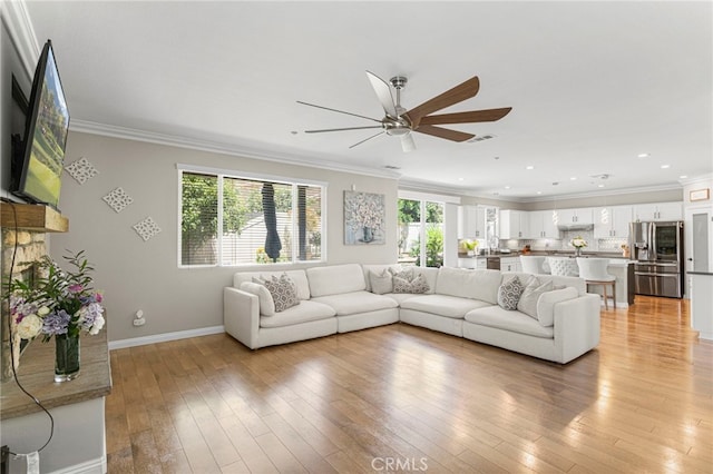 unfurnished living room with a healthy amount of sunlight, crown molding, and light hardwood / wood-style flooring