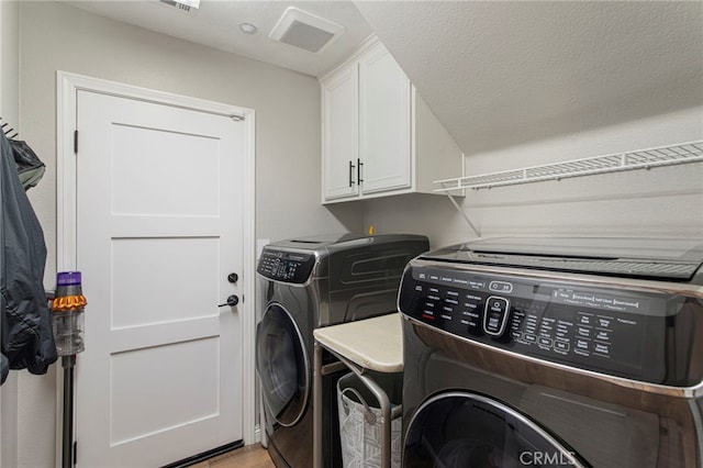 clothes washing area featuring cabinets and independent washer and dryer