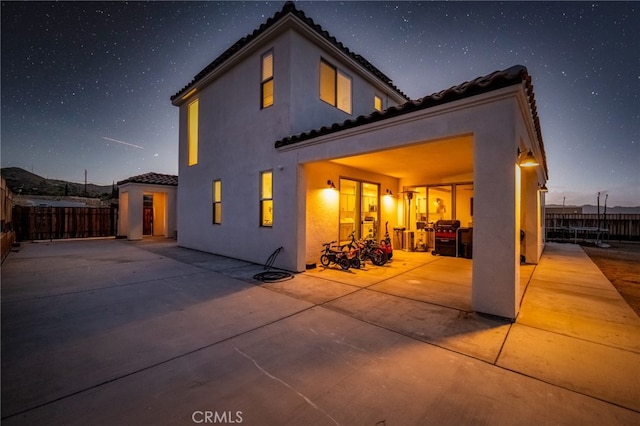 back house at dusk featuring a patio area