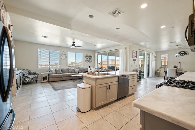 kitchen featuring black dishwasher, a kitchen island with sink, sink, ceiling fan, and stainless steel fridge