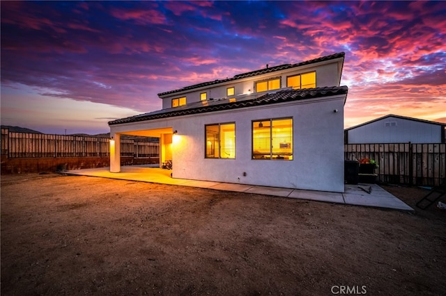 back house at dusk featuring a patio