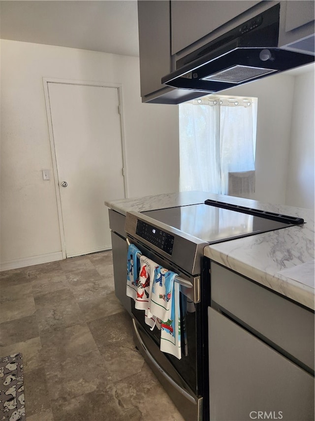 kitchen featuring gray cabinets, exhaust hood, light stone countertops, and stainless steel electric range