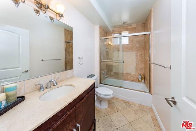 full bathroom with tile patterned floors, vanity, bath / shower combo with glass door, and toilet