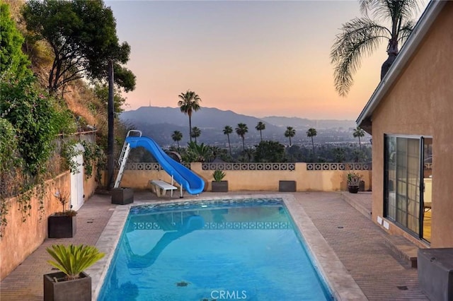 pool at dusk with a mountain view and a water slide