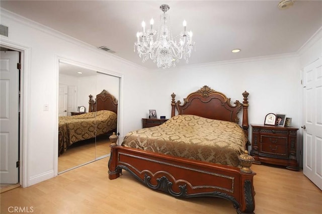 bedroom featuring an inviting chandelier, wood-type flooring, crown molding, and a closet