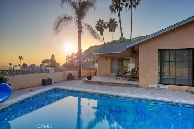 pool at dusk featuring a patio area