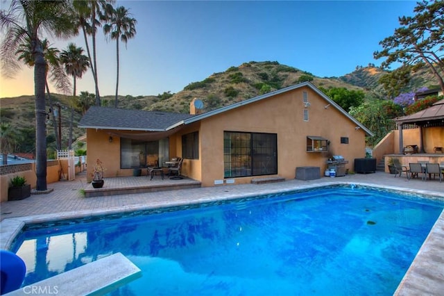 view of pool with a mountain view, a diving board, a patio, and grilling area