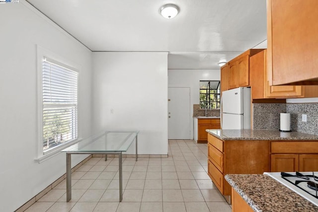 kitchen featuring a wealth of natural light, white appliances, stone counters, and backsplash