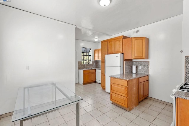 kitchen featuring light stone counters, light tile patterned floors, sink, white appliances, and tasteful backsplash