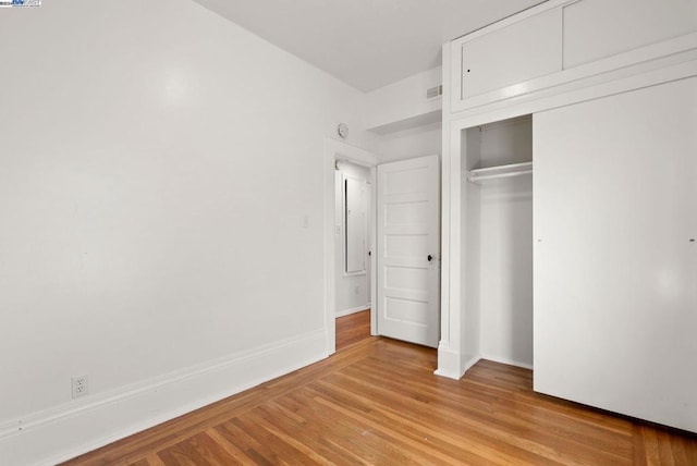 unfurnished bedroom with light wood-type flooring and a closet