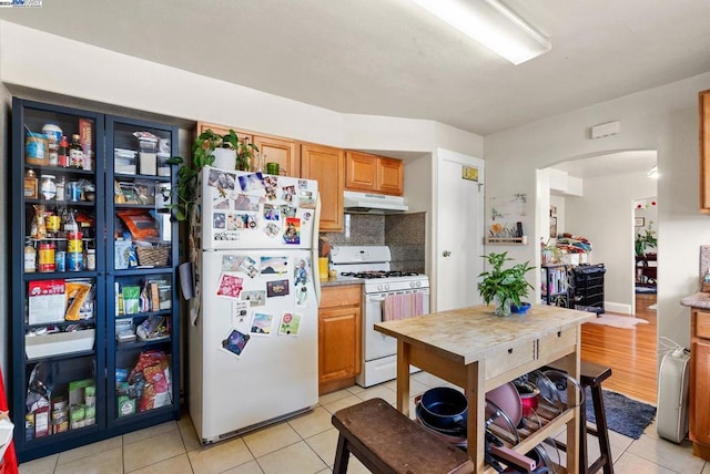 kitchen with light tile patterned flooring, tasteful backsplash, and white appliances