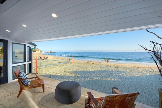 view of patio / terrace featuring a water view and a beach view