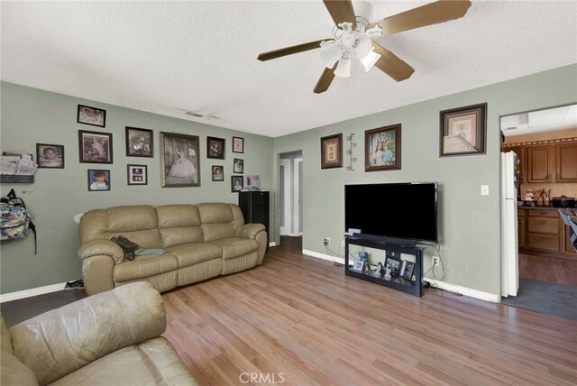 living room with light wood-type flooring, a textured ceiling, and ceiling fan