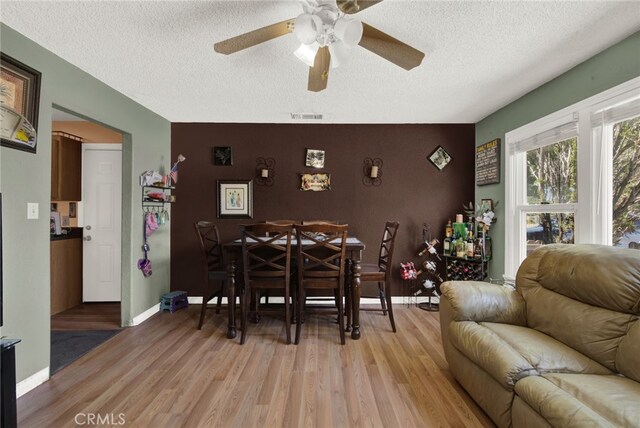 dining room with ceiling fan, a textured ceiling, and light hardwood / wood-style flooring