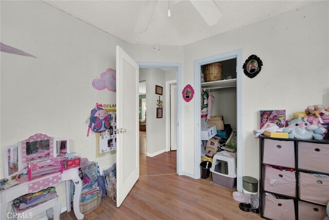 bedroom with a textured ceiling, a closet, ceiling fan, and light hardwood / wood-style floors