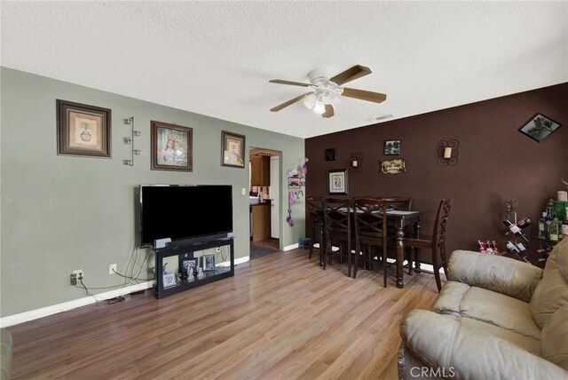 living room featuring ceiling fan, a textured ceiling, and light hardwood / wood-style flooring