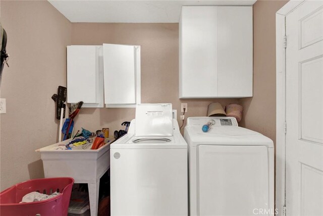 clothes washing area with cabinets and separate washer and dryer