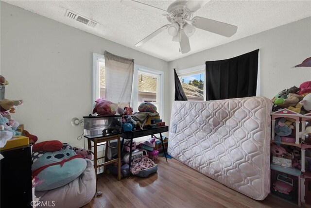 bedroom featuring ceiling fan, wood-type flooring, and a textured ceiling