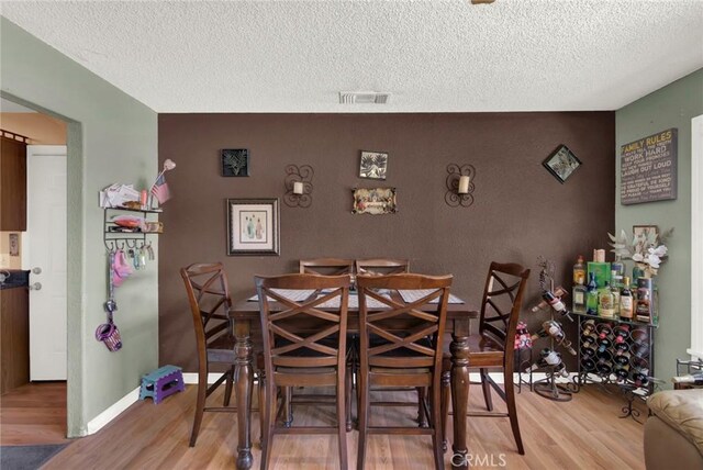 dining room with hardwood / wood-style flooring and a textured ceiling