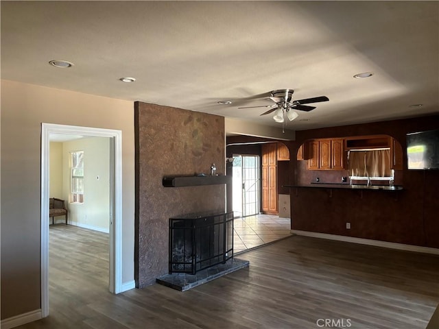 kitchen featuring dark hardwood / wood-style floors, ceiling fan, kitchen peninsula, and a fireplace