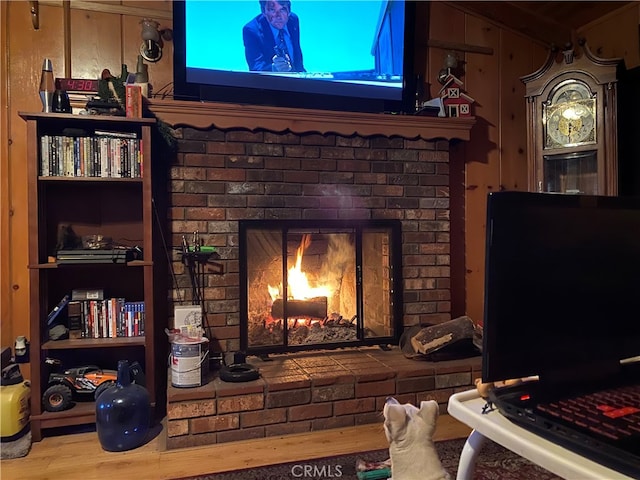 living room featuring a brick fireplace, wooden walls, and hardwood / wood-style floors