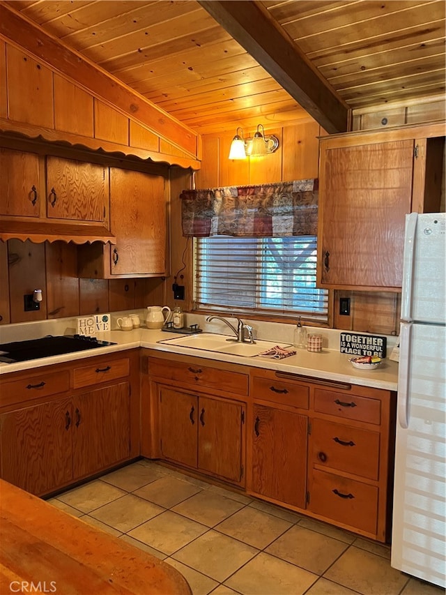 kitchen with white refrigerator, wood ceiling, light tile patterned flooring, sink, and wooden walls