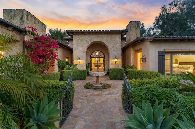 exterior entry at dusk featuring a patio